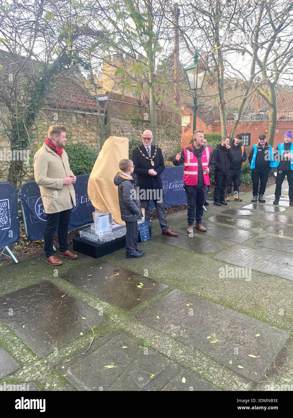 Community members gather in Lincoln of ice sculptures and the Castle walls and the mayor people talking in the street man with a top hat old buildings - Smartphone Captured Stock Image