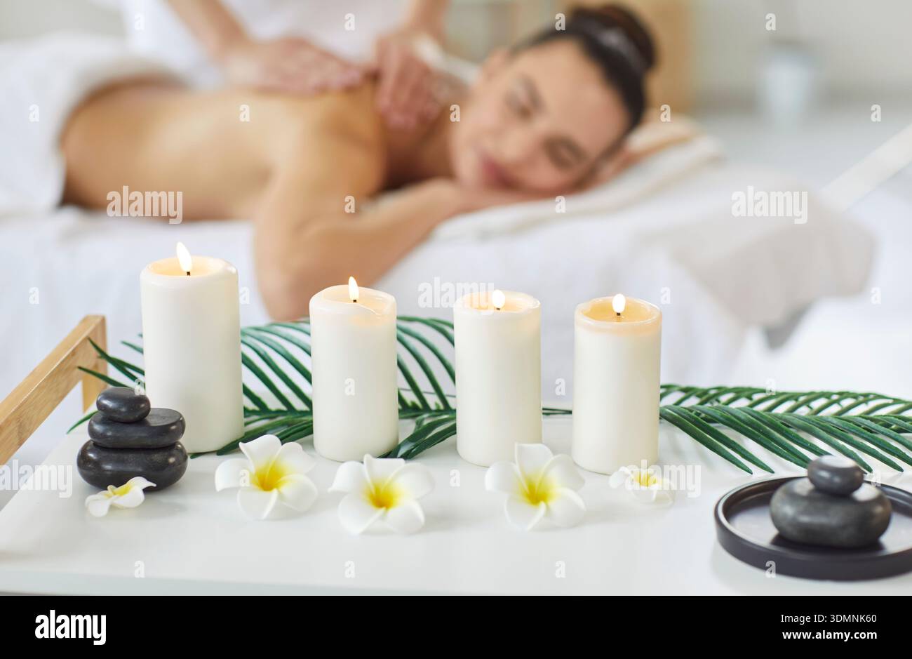 Beautiful woman enjoying back massage and aromatherapy in spa salon lying on couch in background. Stock Photo