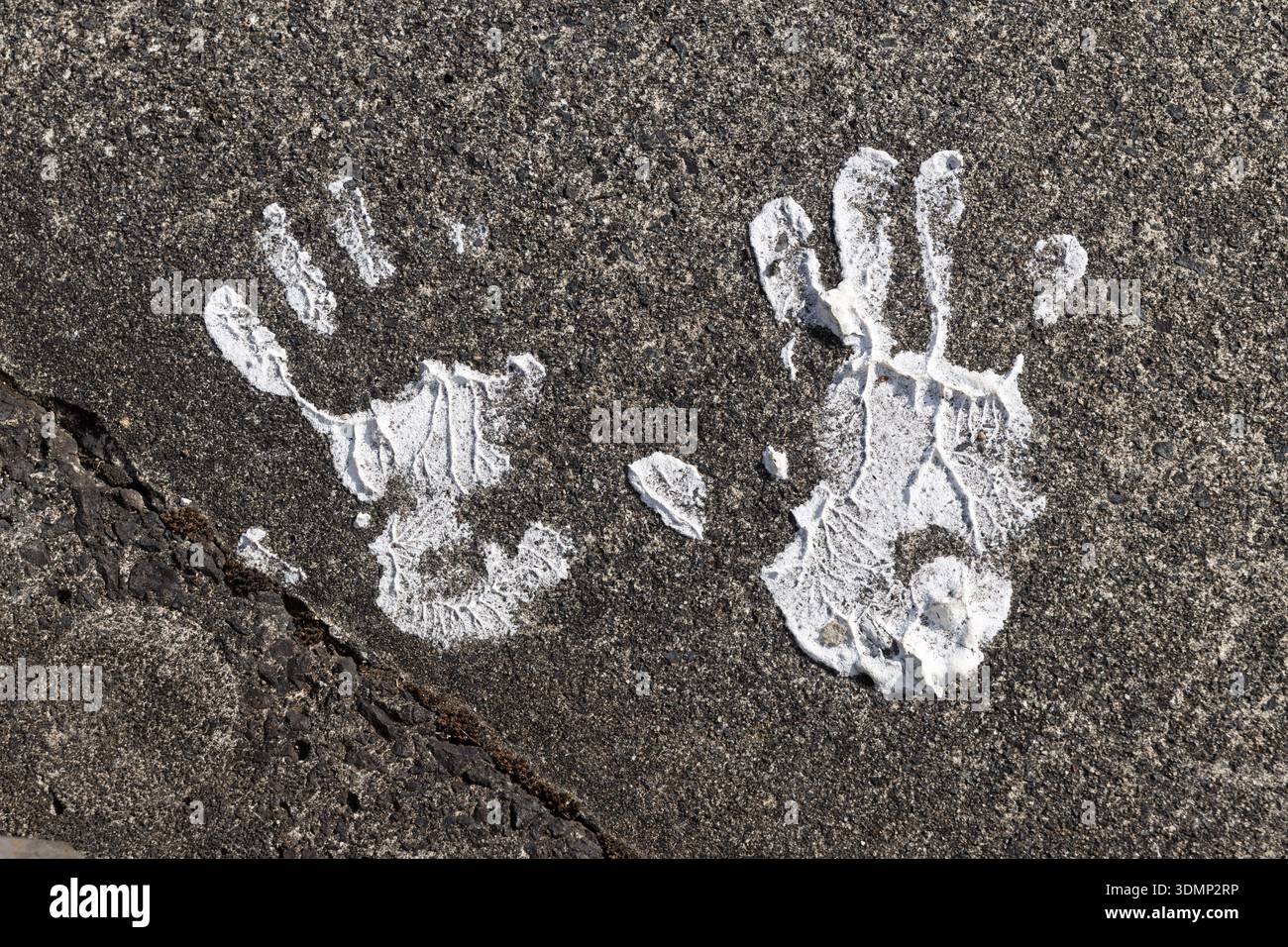 White painted handprints on rough asphalt surface, close-up Stock Photo