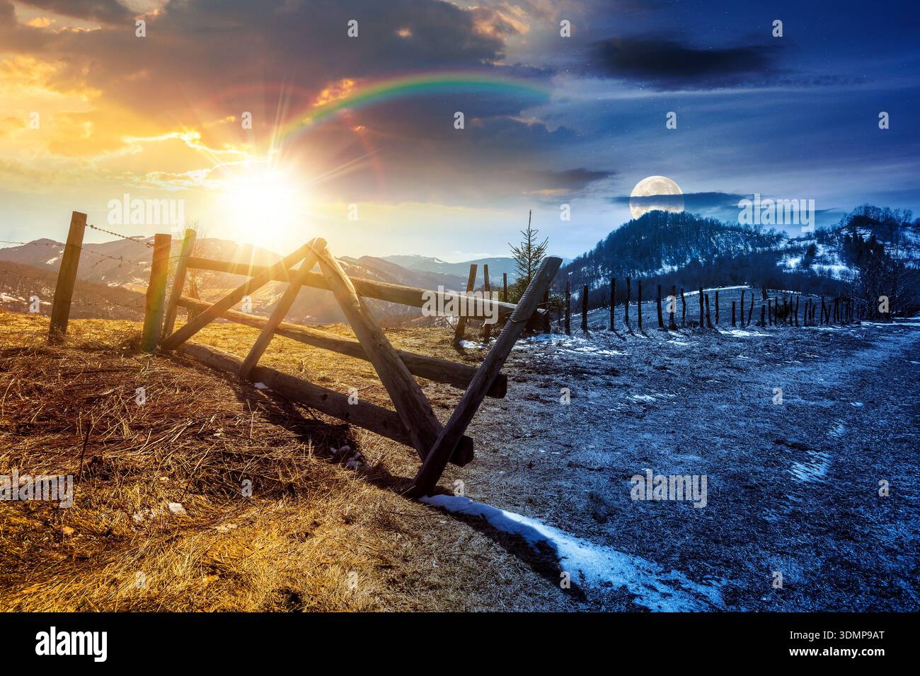 rural landscape in mountains in early spring under blue sky. day and night time change concept. snow covered hill with barbed wire fence with sun and Stock Photo