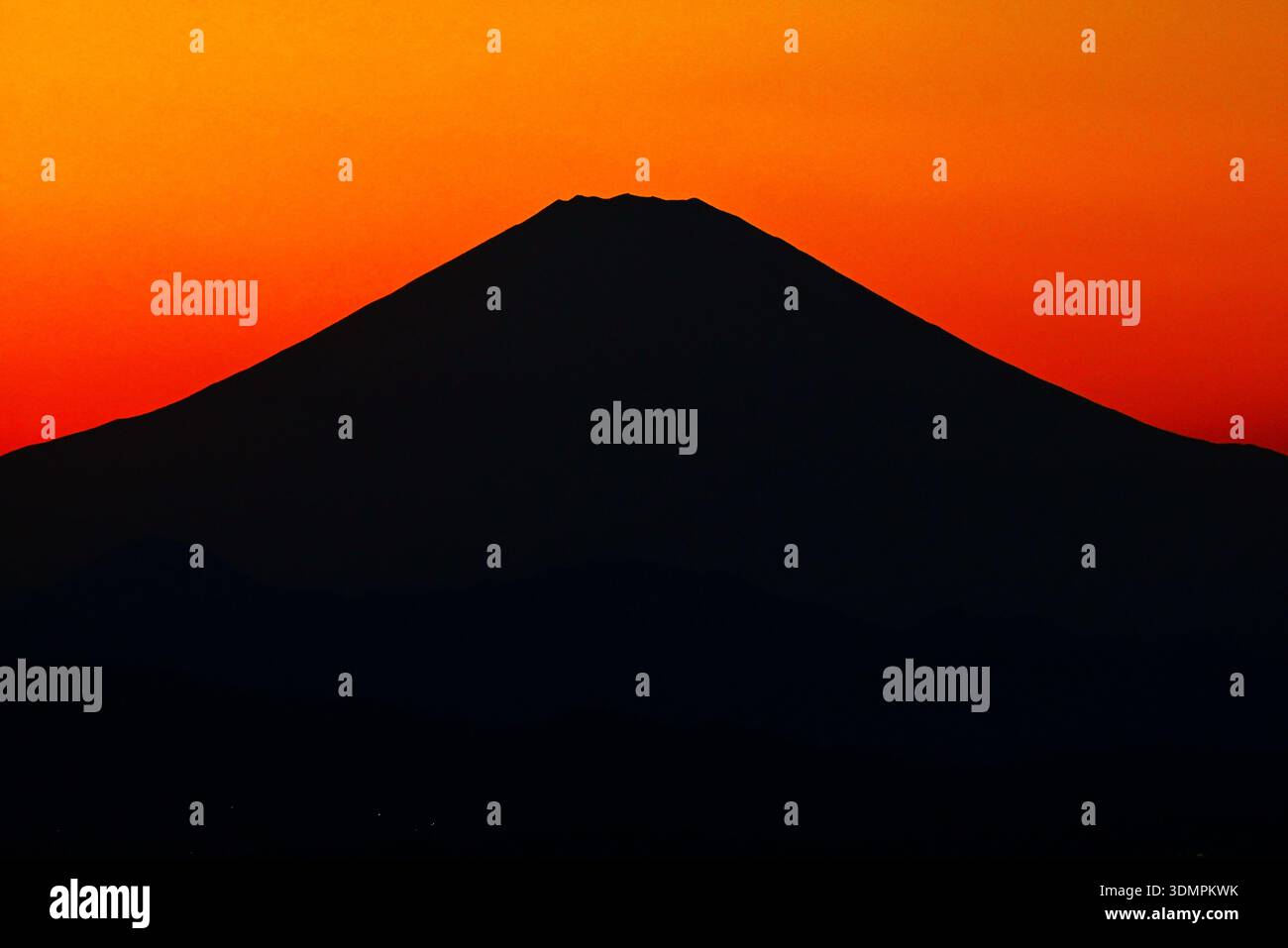 The sunset silhouette of Mt. Fuji. As the sun sets, the color of the sky deepens and Mt. Fuji stands out like a black silhouette. Stock Photo