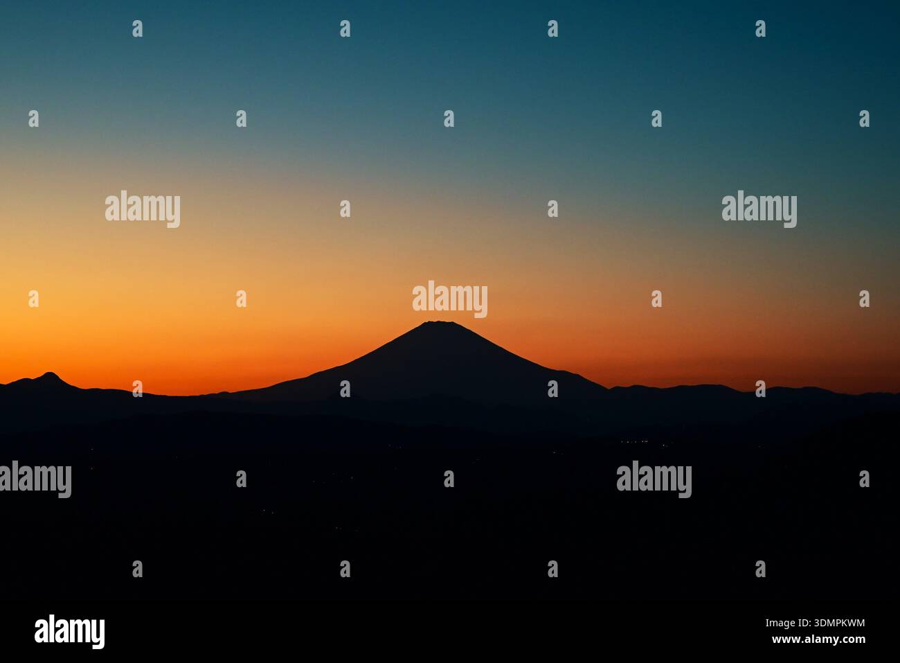 The sunset silhouette of Mt. Fuji. As the sun sets, the color of the sky deepens and Mt. Fuji stands out like a black silhouette. Stock Photo