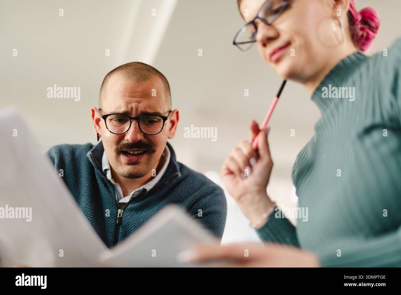 Collaboration between two business professionals in a modern office setting while discussing project details and analyzing reports Stock Photo