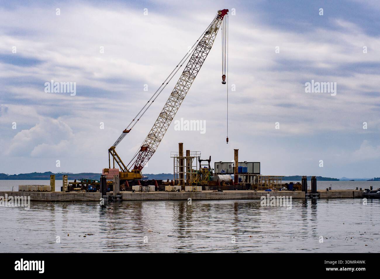 Barge Engine A yellow lattice boom crawler crane operates on a floating industrial ...