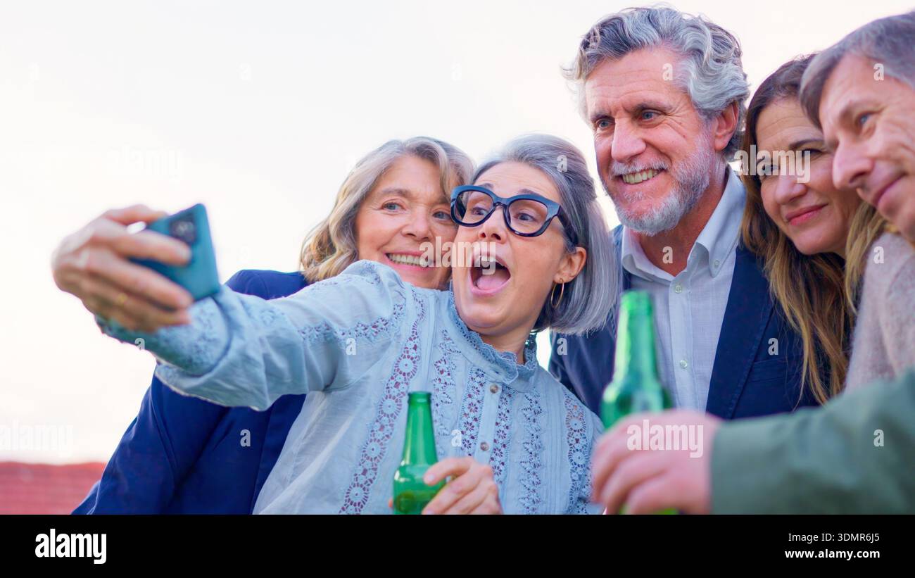 Mature friends drinking beer and taking a selfie outdoors Stock Photo