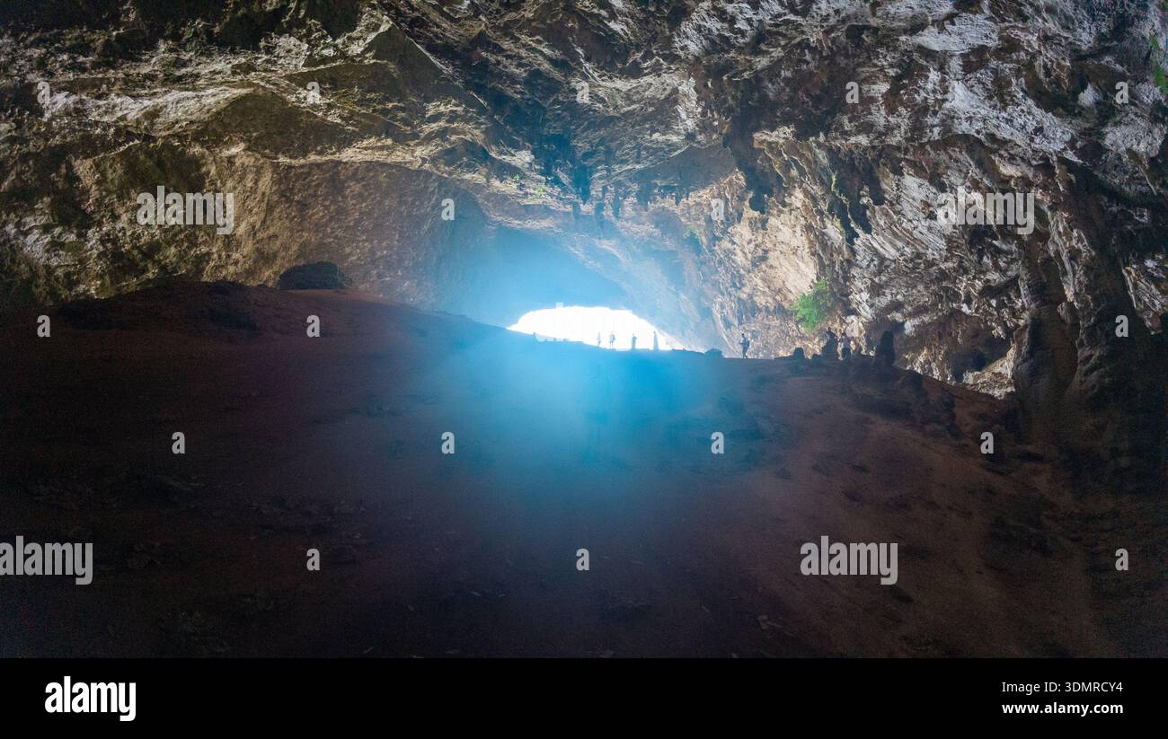 Inside a large rocky cave with rough limestone ceiling, dark floor, and ...