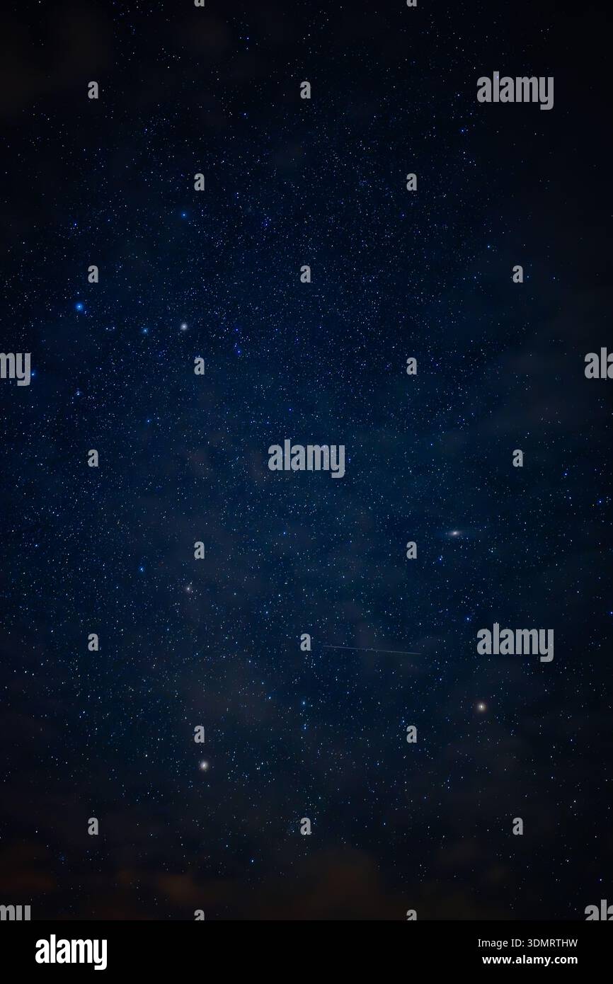 A serene night sky filled with countless stars and drifting clouds. A ...