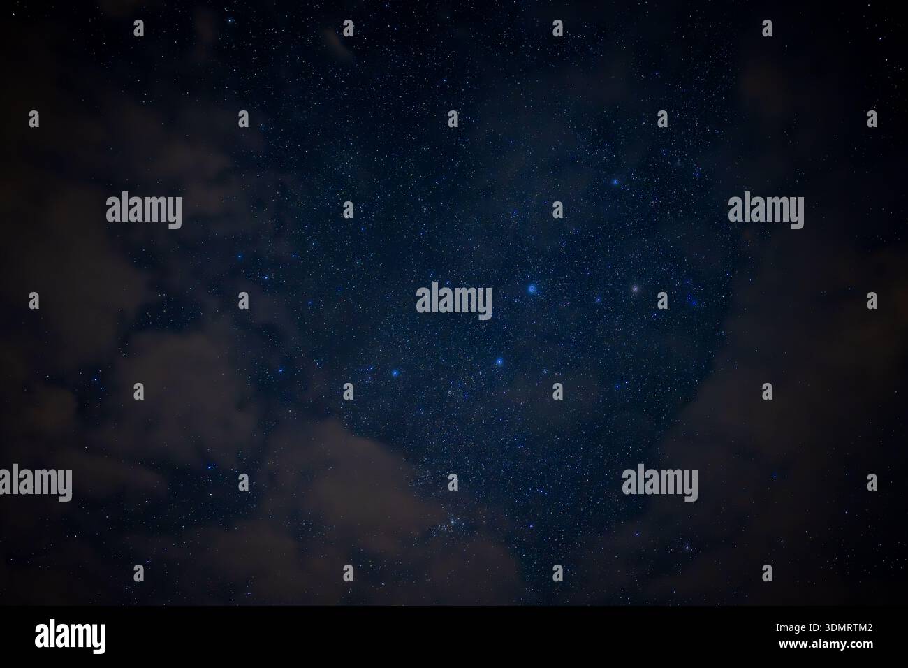 A serene night sky filled with countless stars and drifting clouds. The ...