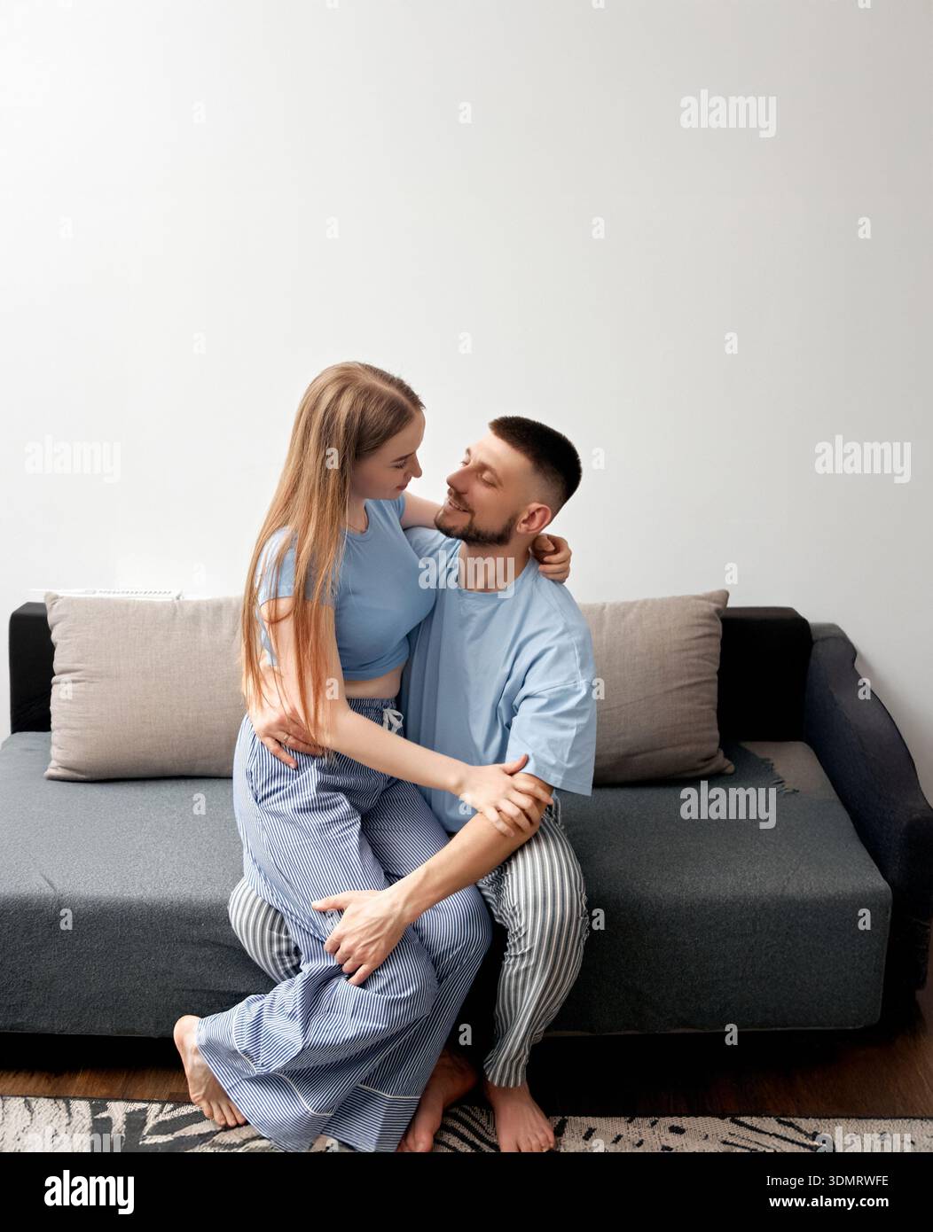 Two people are sitting on a couch in a living room. They are facing ...