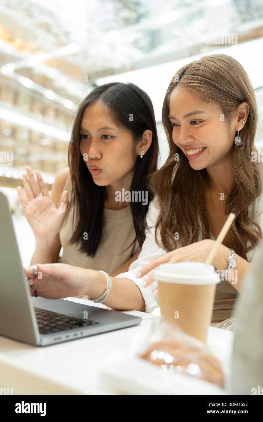 Two young asian women having video call using laptop Stock Photo