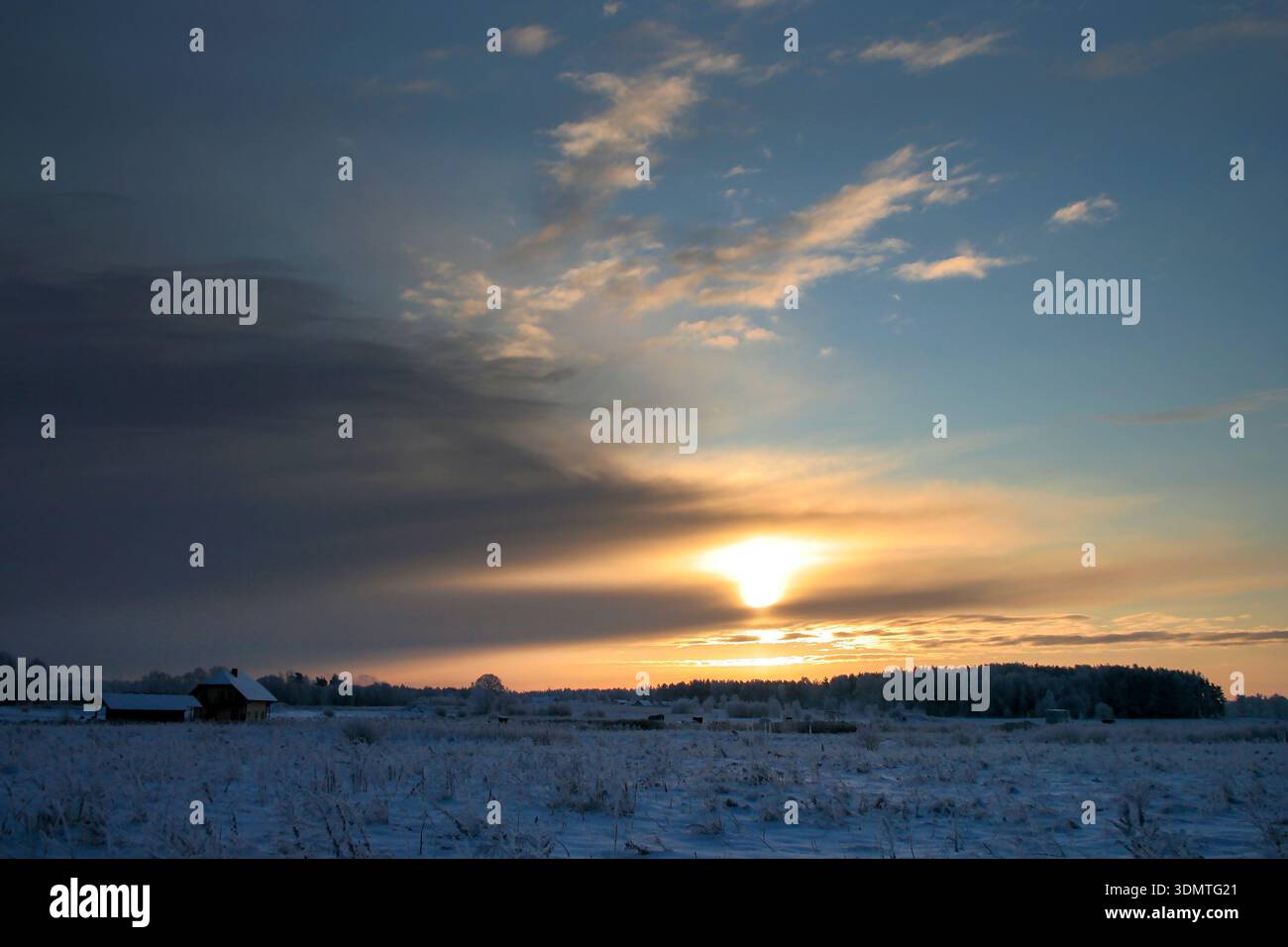 Winter Sunset over Snowy Field with Distant Cabin Stock Photo