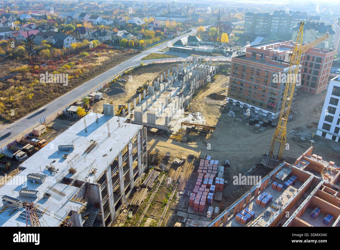 Builders work on constructing new buildings at construction site with using cranes in city Stock Photo