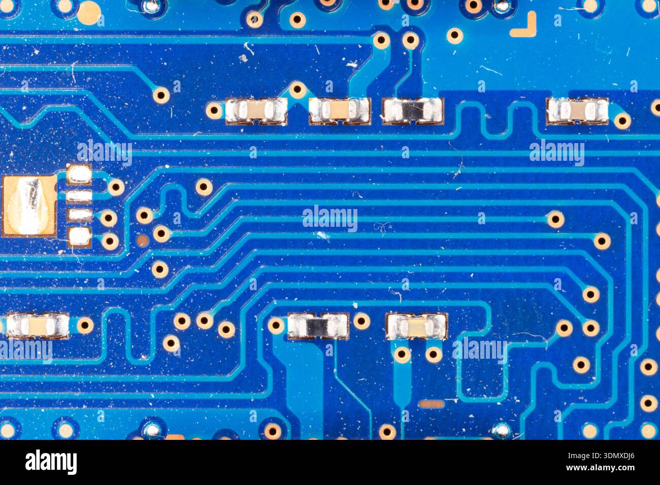 Blue circuit board surface featuring electronic pathways and tiny components Stock Photo