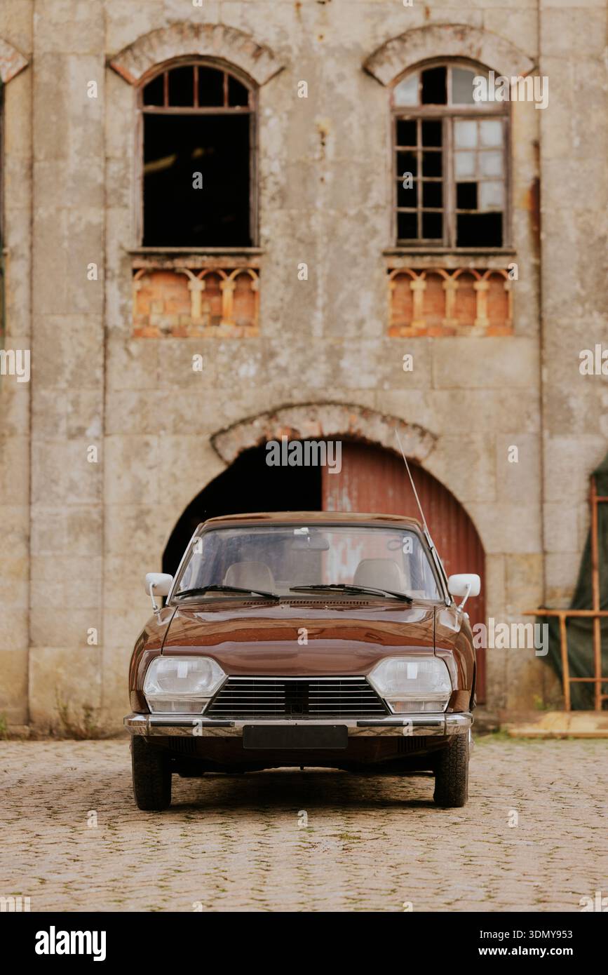 A classic vintage car is parked on a cobblestone path in front of an ...