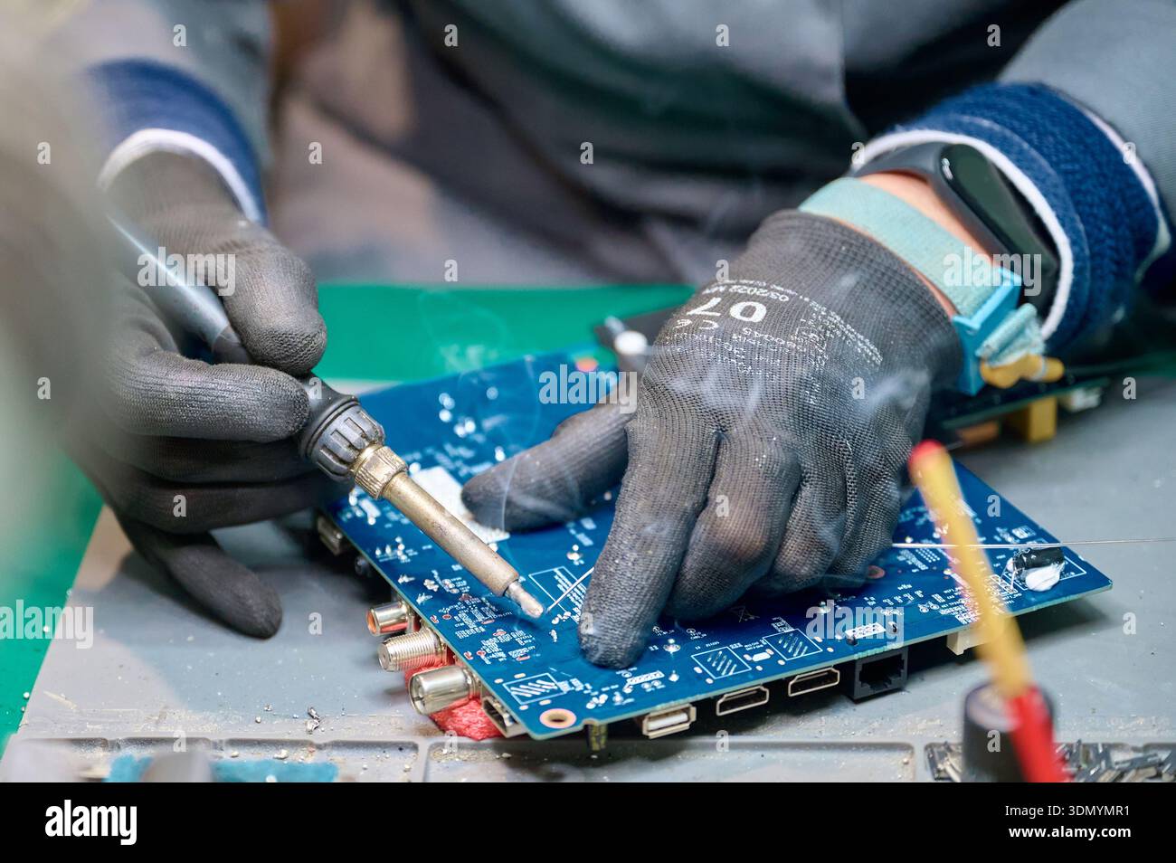 Skilled technician repairs electronic circuit board with soldering tool in workshop Stock Photo