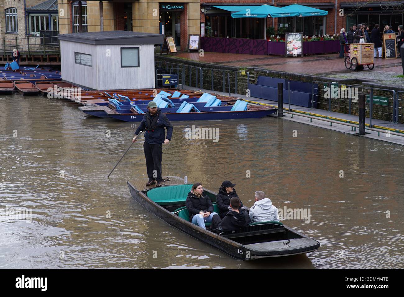 Punter steering a traditional punt with passengers on the muddy River Cam in Cambridge on a winter day. Cambridge,England Stock Photo