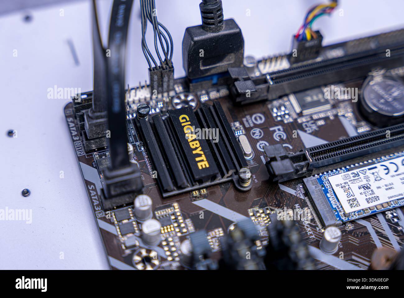 Macro close up of computer motherboard with SSD, PCIe slot, wiring and cooling hardware inside modern desktop system. Stock Photo