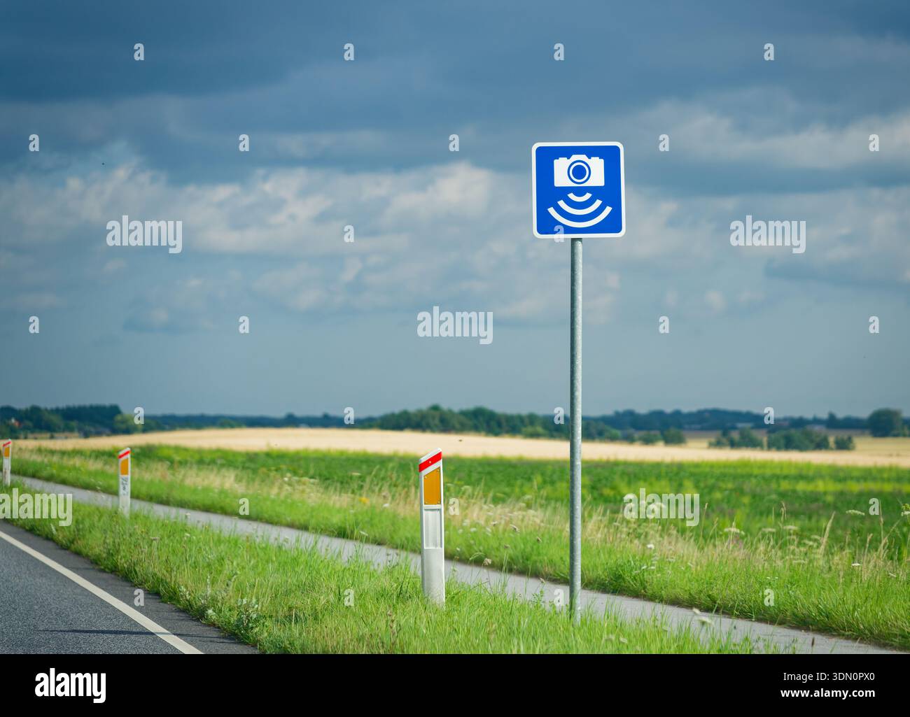 A roadside sign shows a camera icon with radiating waves, warning of ...