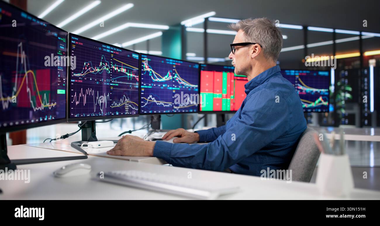 Experienced Trader Analyzing Market Trends On Computer Screens At Exchange. Stock Photo