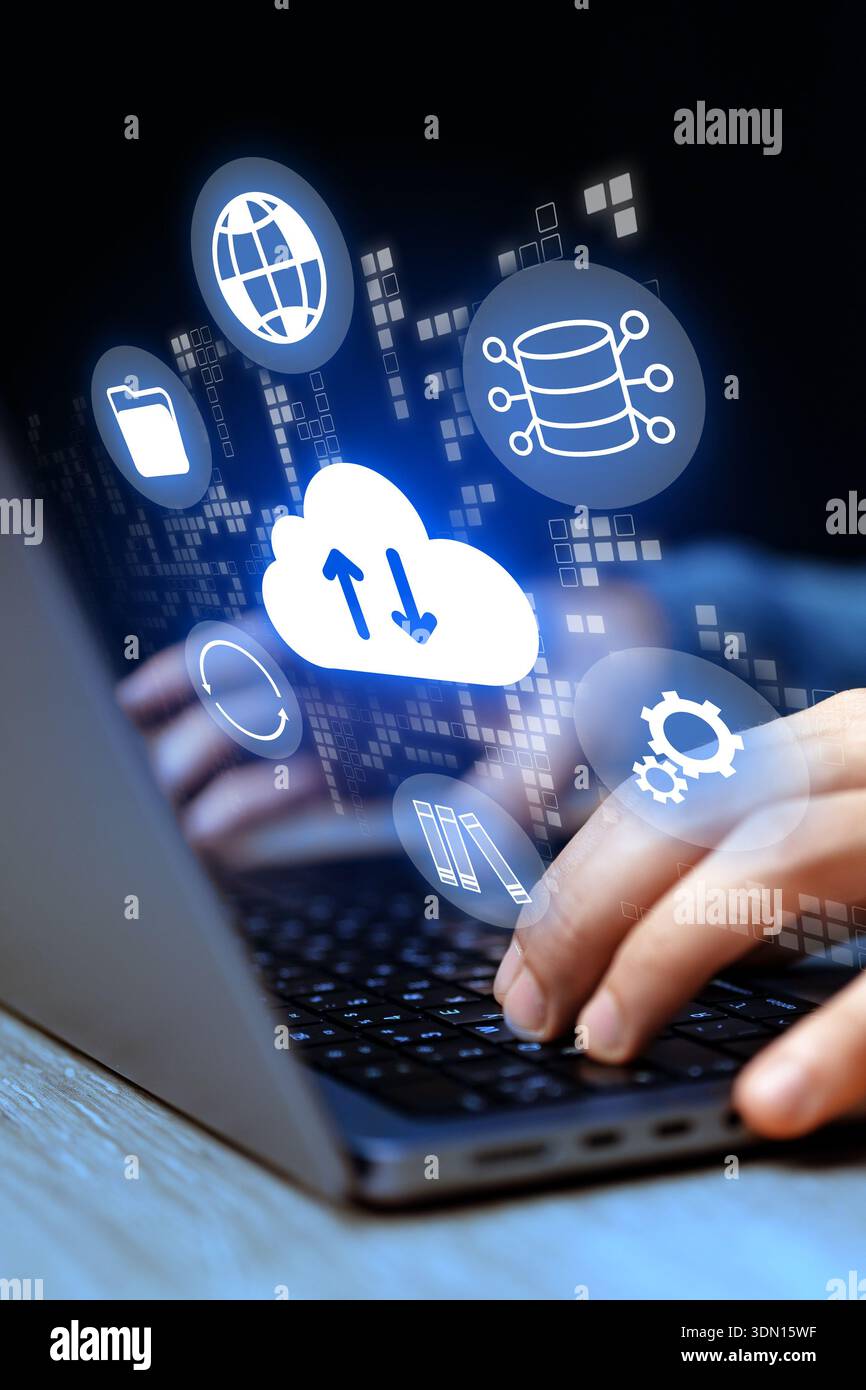 Hands using a laptop with cloud computing icons in a dark setting Stock Photo