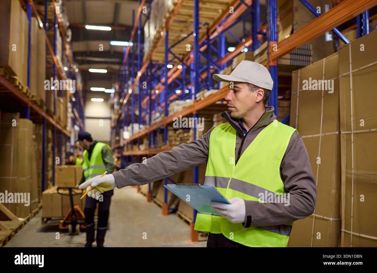 Warehouse logistics worker directing loading while checking inventory on shelves Stock Photo