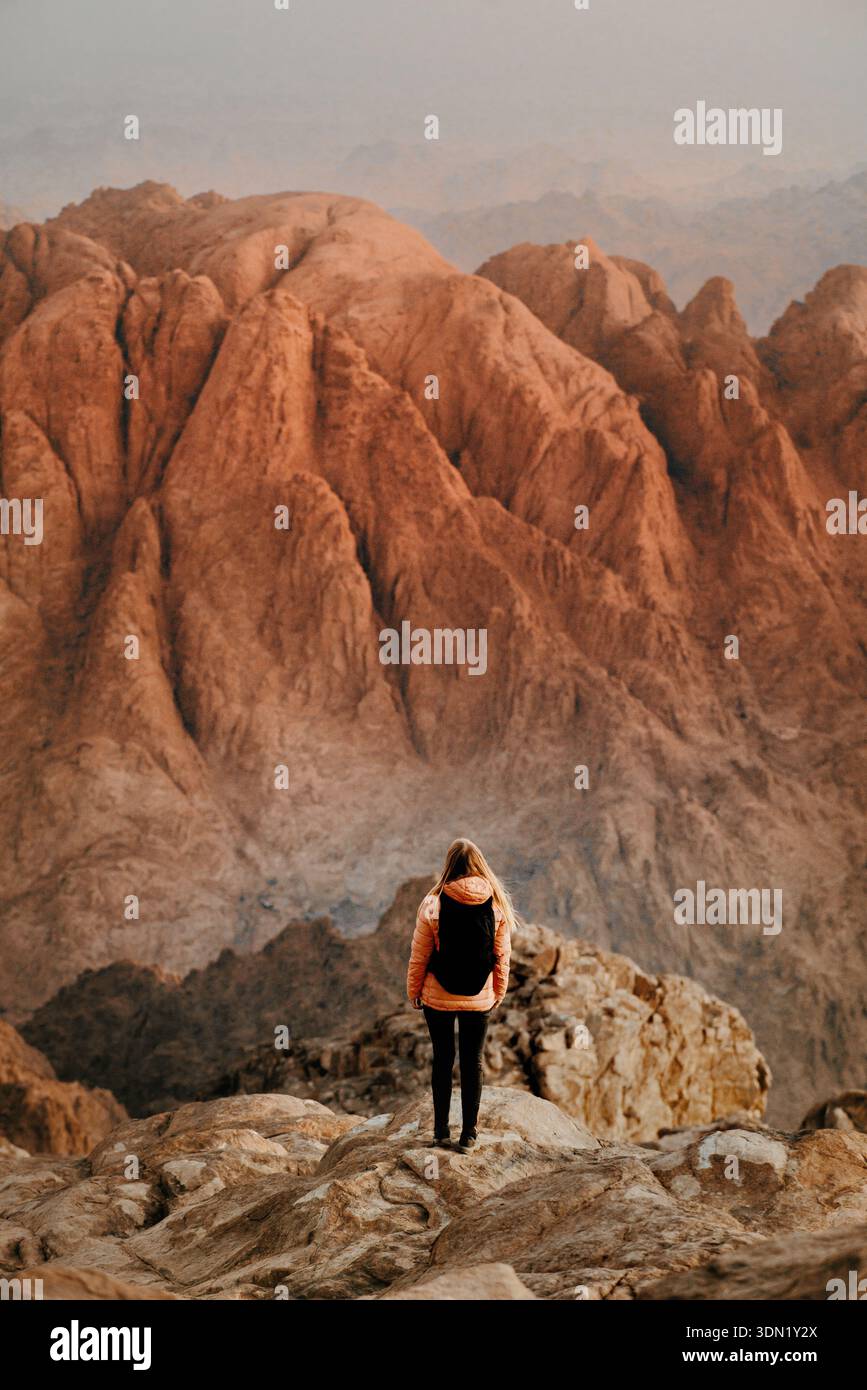 Woman hiking solo in Egypt climbing Sinai Mount, girl traveler enjoying sunrise rocks view adventure vacations trip outdoor freedom harmony with natur Stock Photo