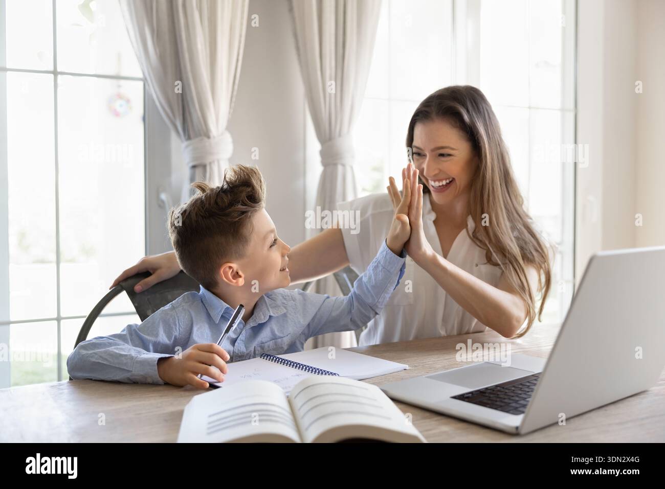 Mother giving high five to son during studying at home Stock Photo