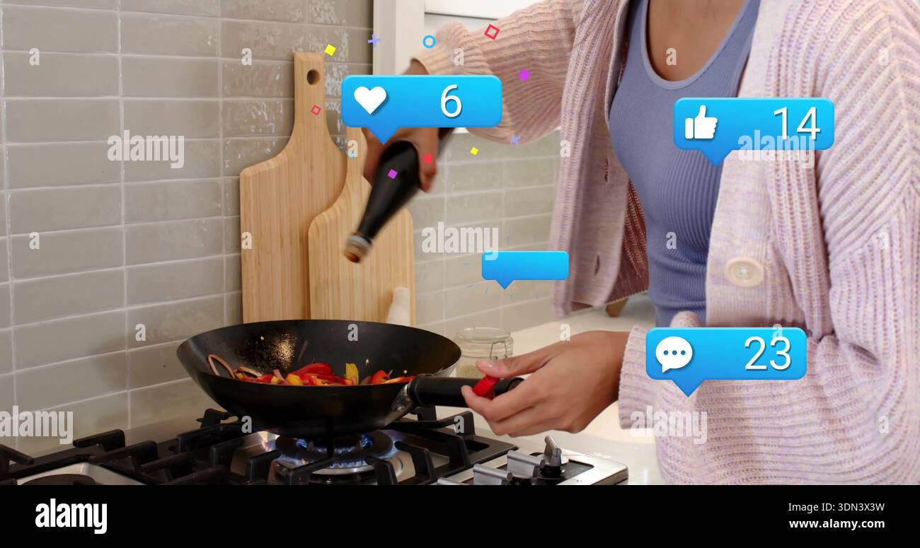 Pouring cook lilac-top pink-cardigan tilting brown bottle over black wok on lit burner, copy space Stock Photo