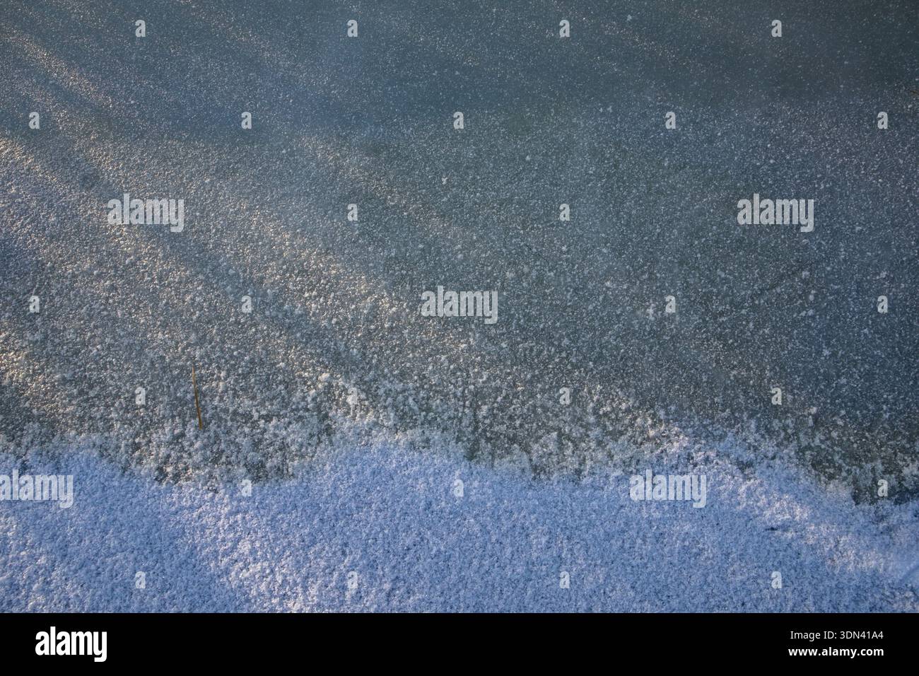 Frozen ice surface with snow layer and subtle winter light texture Stock Photo