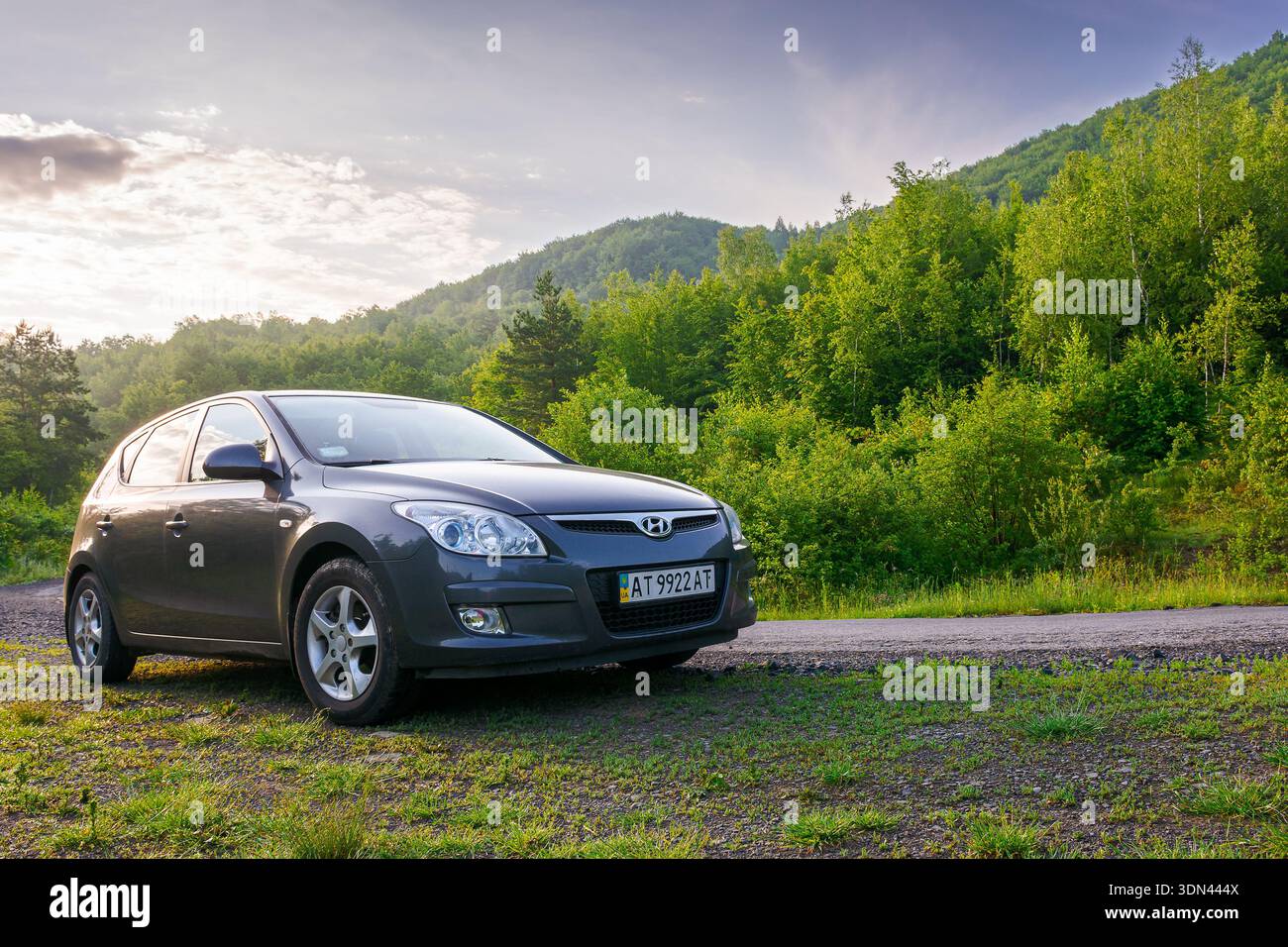 perechyn, ukraine - jun 10 2020: car near winding country road on summer sunrise. beautiful view of mountain in the background. automotive photography Stock Photo