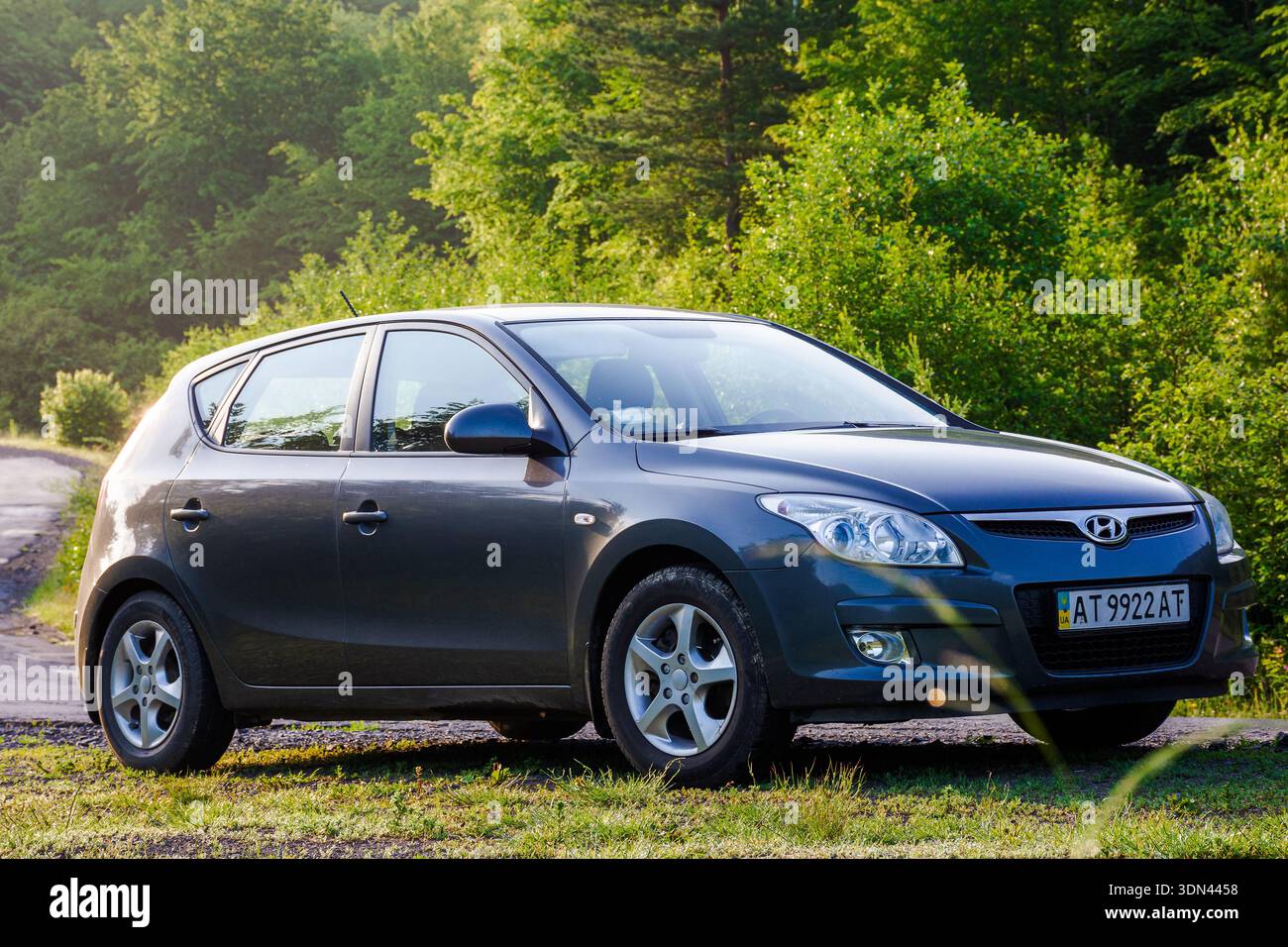 perechyn, ukraine - jun 10 2020: car near winding country road on summer sunrise. beautiful view of mountain in the background. automotive photography Stock Photo