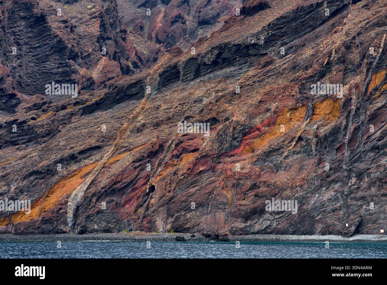 Colorful layered volcanic rock formations with orange red and black ...