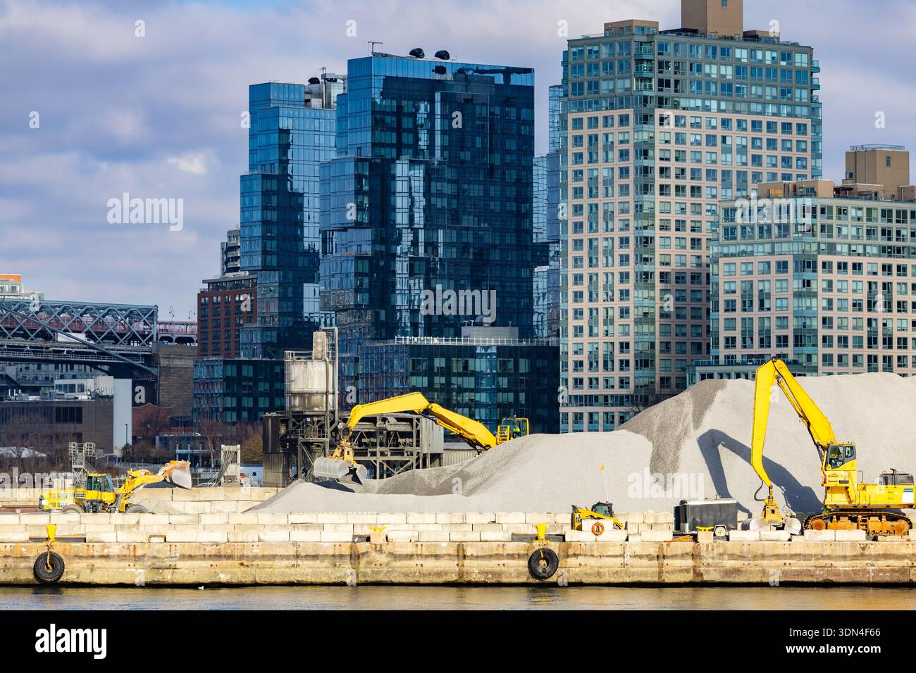Excavators working at waterfront construction site with gravel piles ...