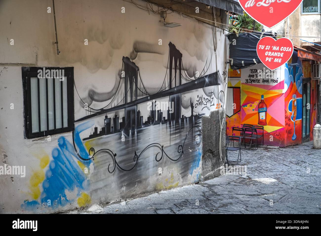 Street art and graffiti in the Quartieri Spagnoli (Spanish Quarter), Napoli, Italy. Mural depicts NYC skyline contrast with local bar advertisements a Stock Photo
