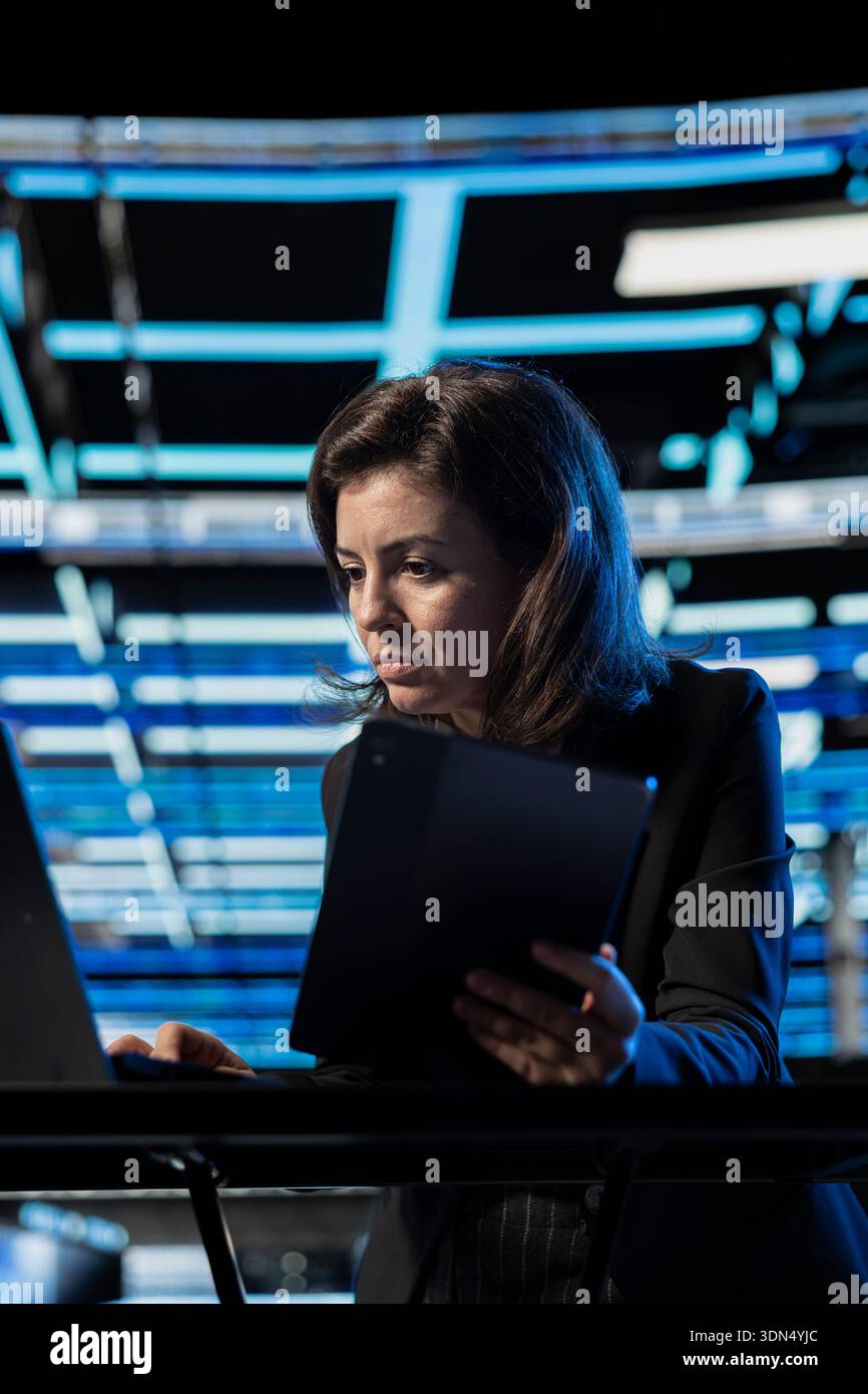 Configuring firewall, devices and programmer in data center verifying security patches. Applying equipment vulnerability scans, IT expert, laptop and tablet in server hub Stock Photo