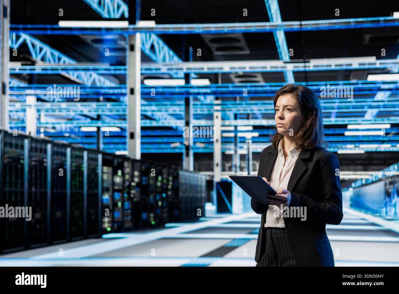 Data center manager using tablet, managing server virtualization. System administrator using device in server room, doing upgrades sustaining long term infrastructure reliability Stock Photo