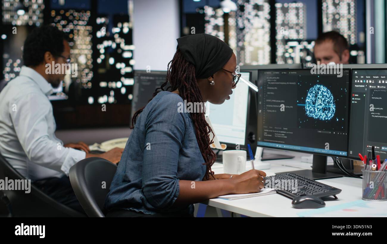 Programmer taking notes at desk in Silicon Valley company office, developing apps. IT expert using machine learning to do coding, writing on notepad, debugging applications to resolve issues Stock Photo