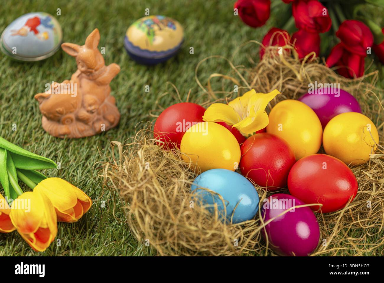 Colourful easter eggs and an Easter bunny with spring flowers on grass Stock Photo