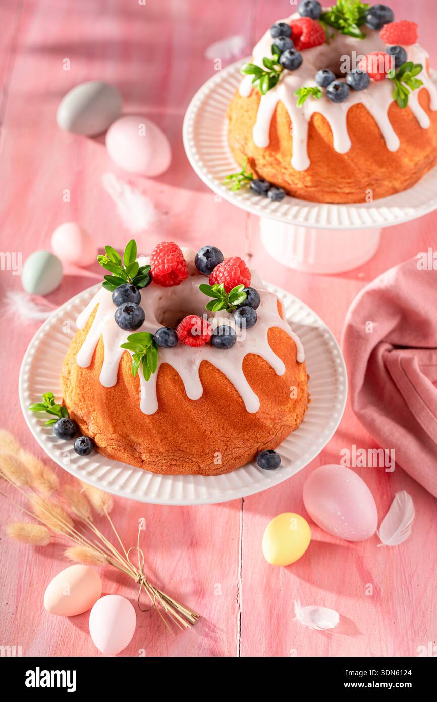 Delicious ring cake for Easter on holiday table with decorations. Easter spring background with flowers and easter eggs. Stock Photo