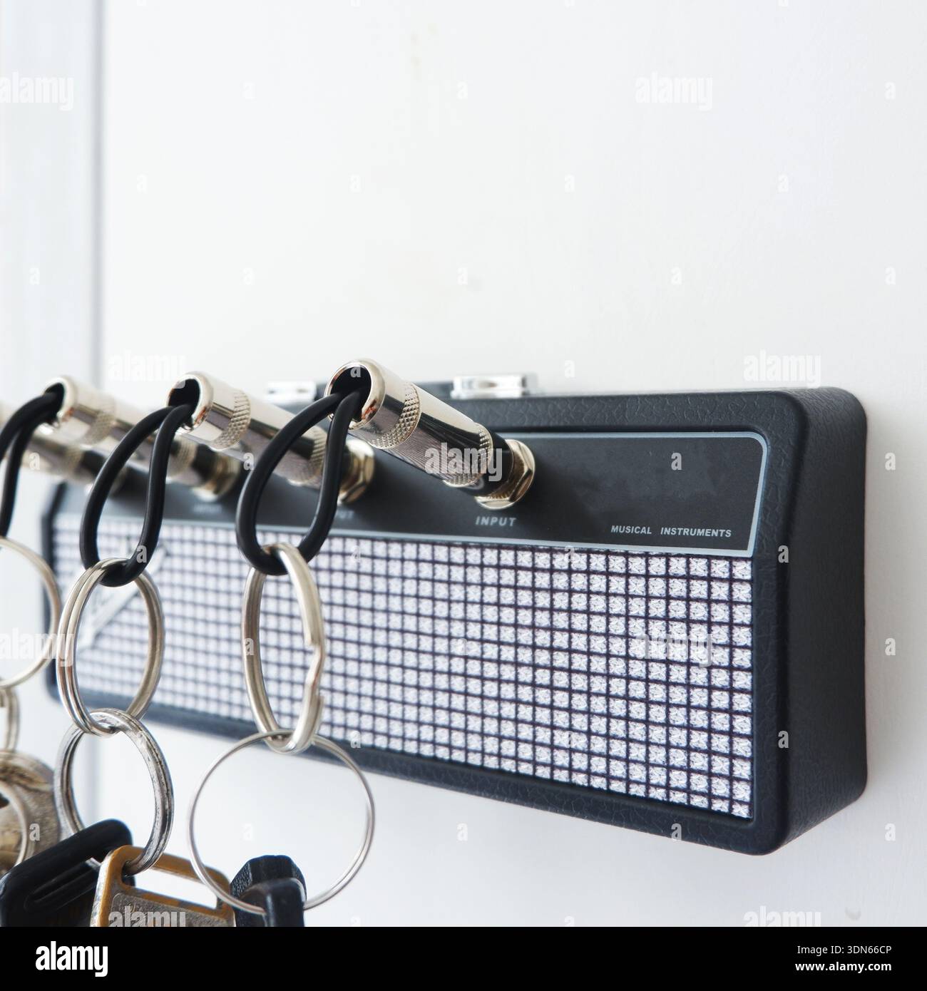 Creative Guitar Amp Key Holder with Jack Plug Keychains on White Wall Stock Photo