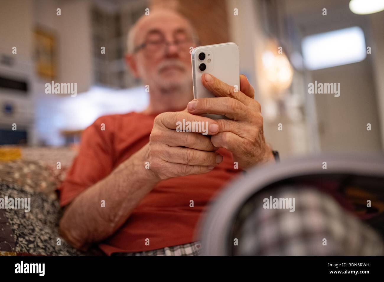Elderly man holding and using a smartphone. Stock Photo