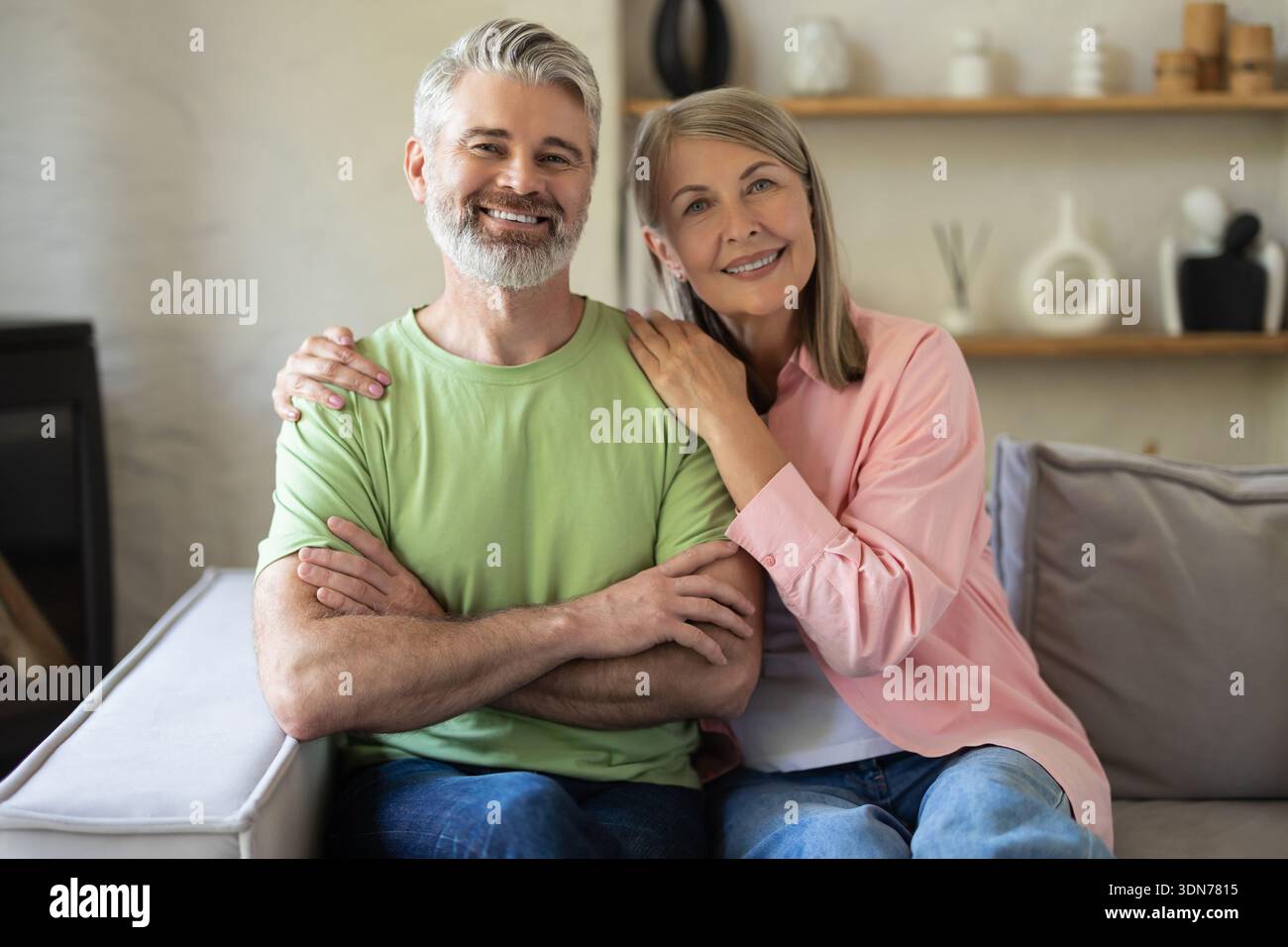 Smiling senior couple posing for portrait while sitting on sofa Stock Photo