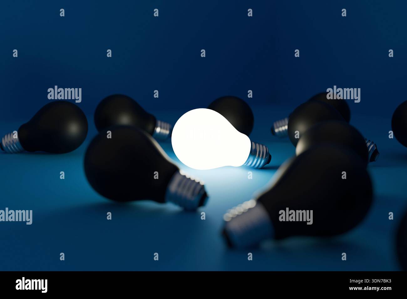Glowing light bulb surrounded by many black bulbs on a deep blue background. Concept of a unique bright idea, standing out from the crowd, individuali Stock Photo