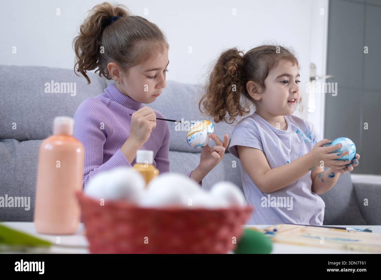 Two sisters decorating Easter eggs at home Stock Photo