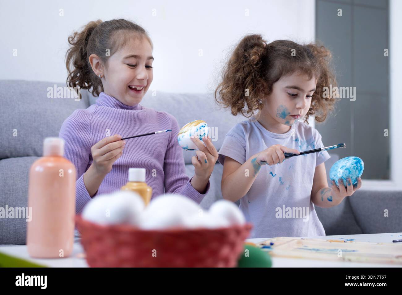 Two sisters decorating Easter eggs at home Stock Photo