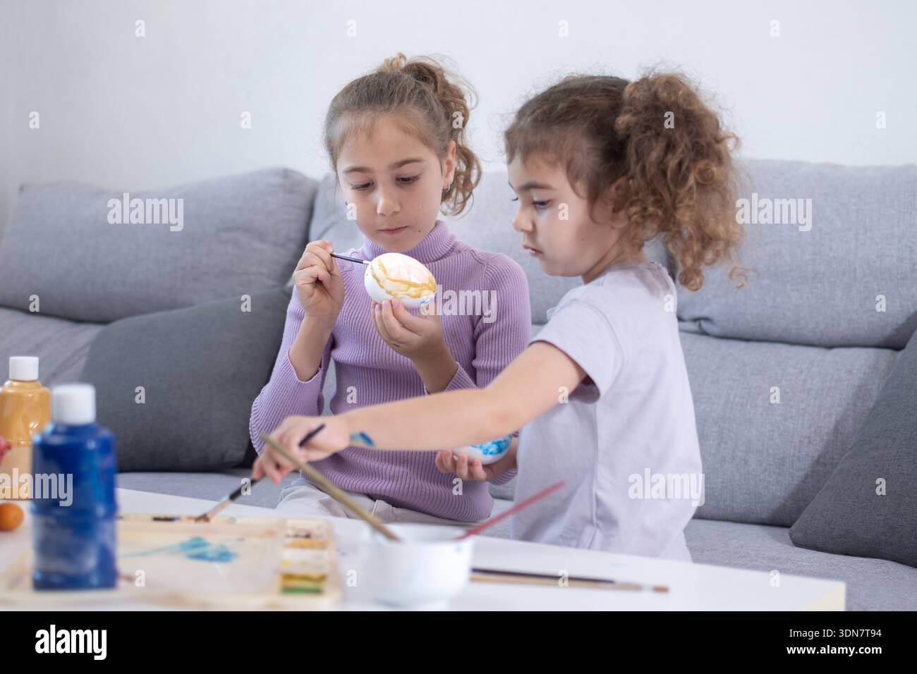 Two sisters decorating Easter eggs at home Stock Photo