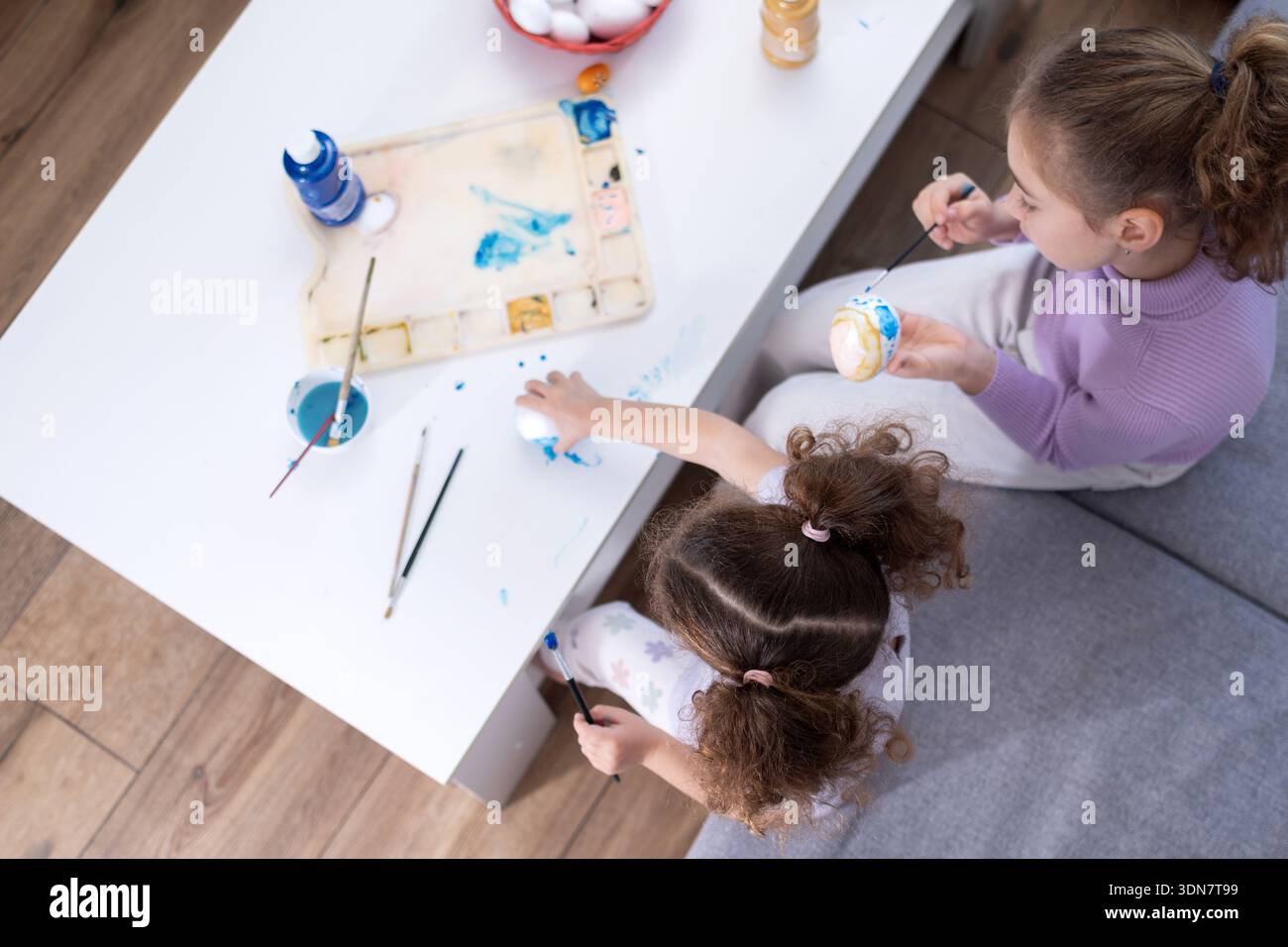 Two sisters decorating Easter eggs at home Stock Photo