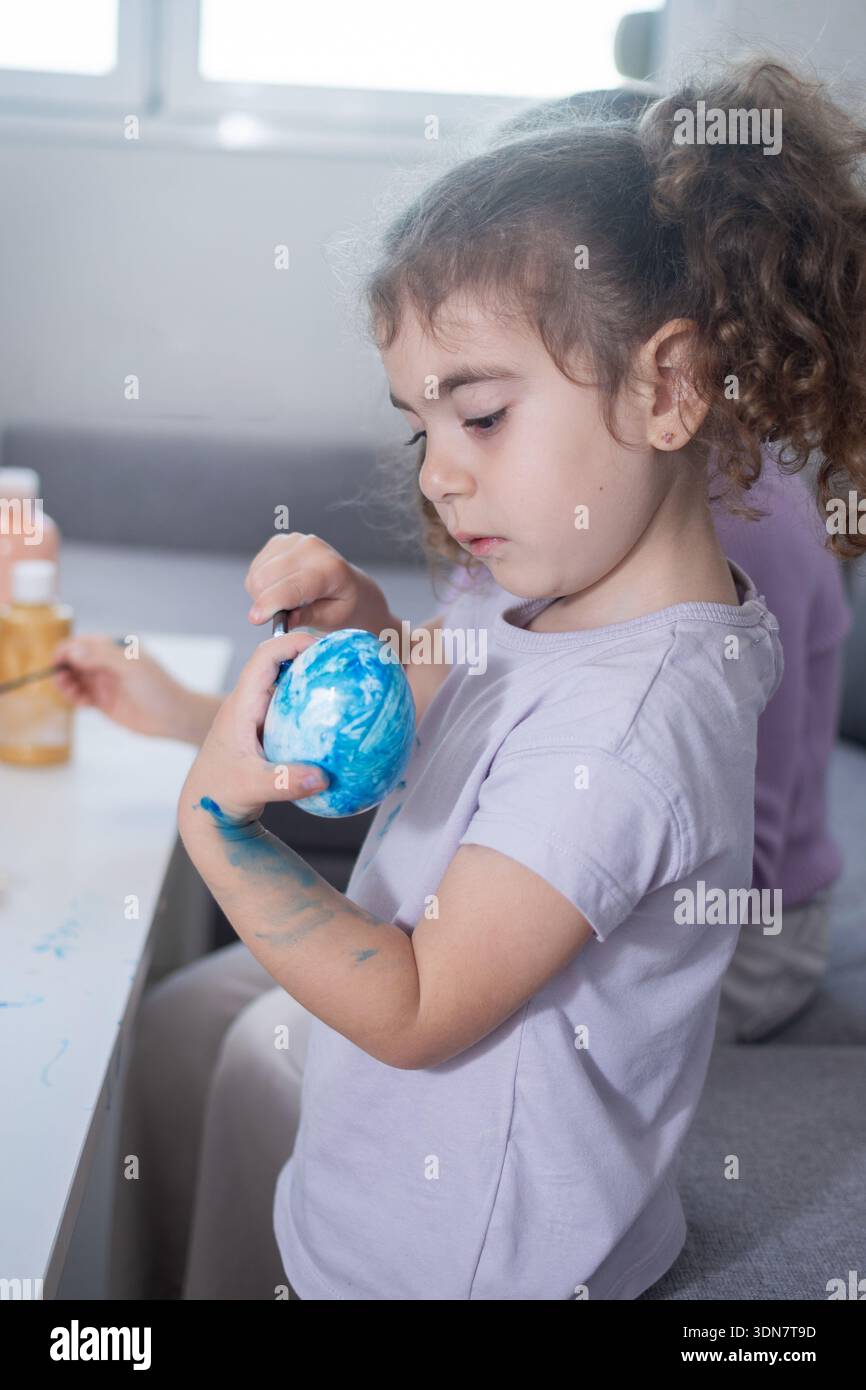 Two sisters decorating Easter eggs at home Stock Photo