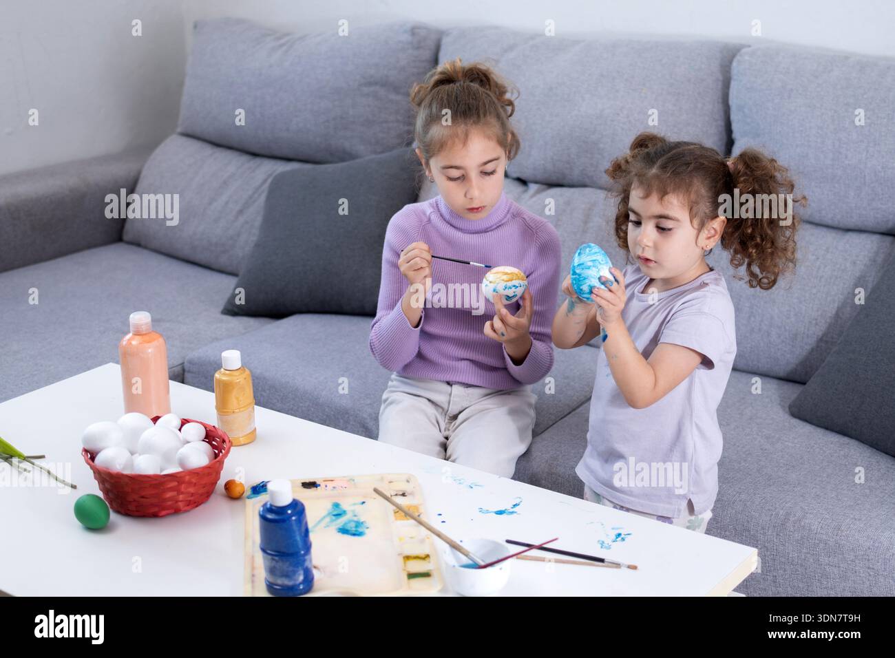 Two sisters decorating Easter eggs at home Stock Photo