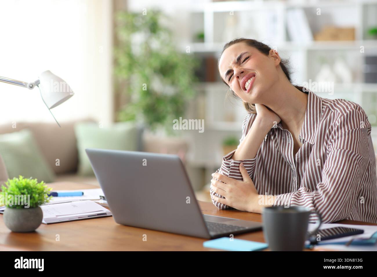Self employed suffering neck ache while working at home Stock Photo